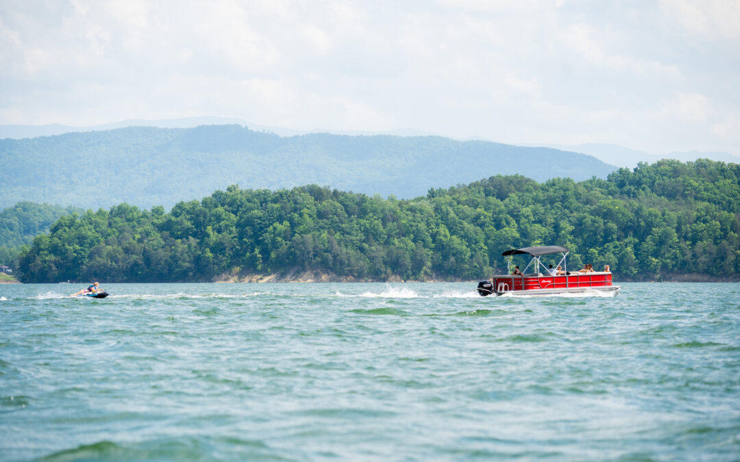 Pontoon boat pulling tube on Lake, mountains in background