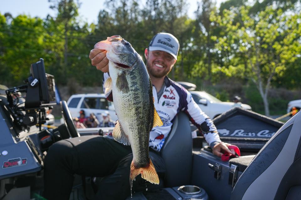 Man sitting in bass boat holding large mouth bass