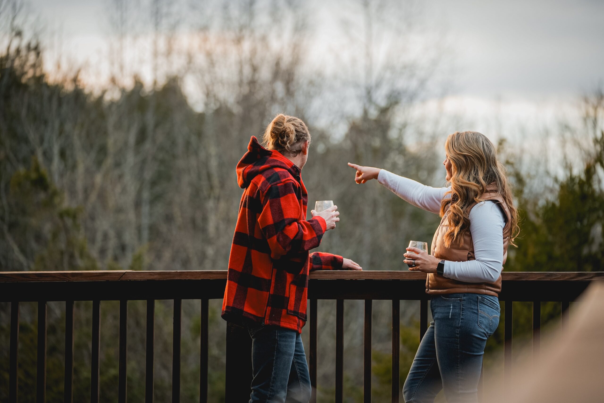 Couple overlooking cabin deck at a beautiful evening sky. The woman is pointing to something off in the distance
