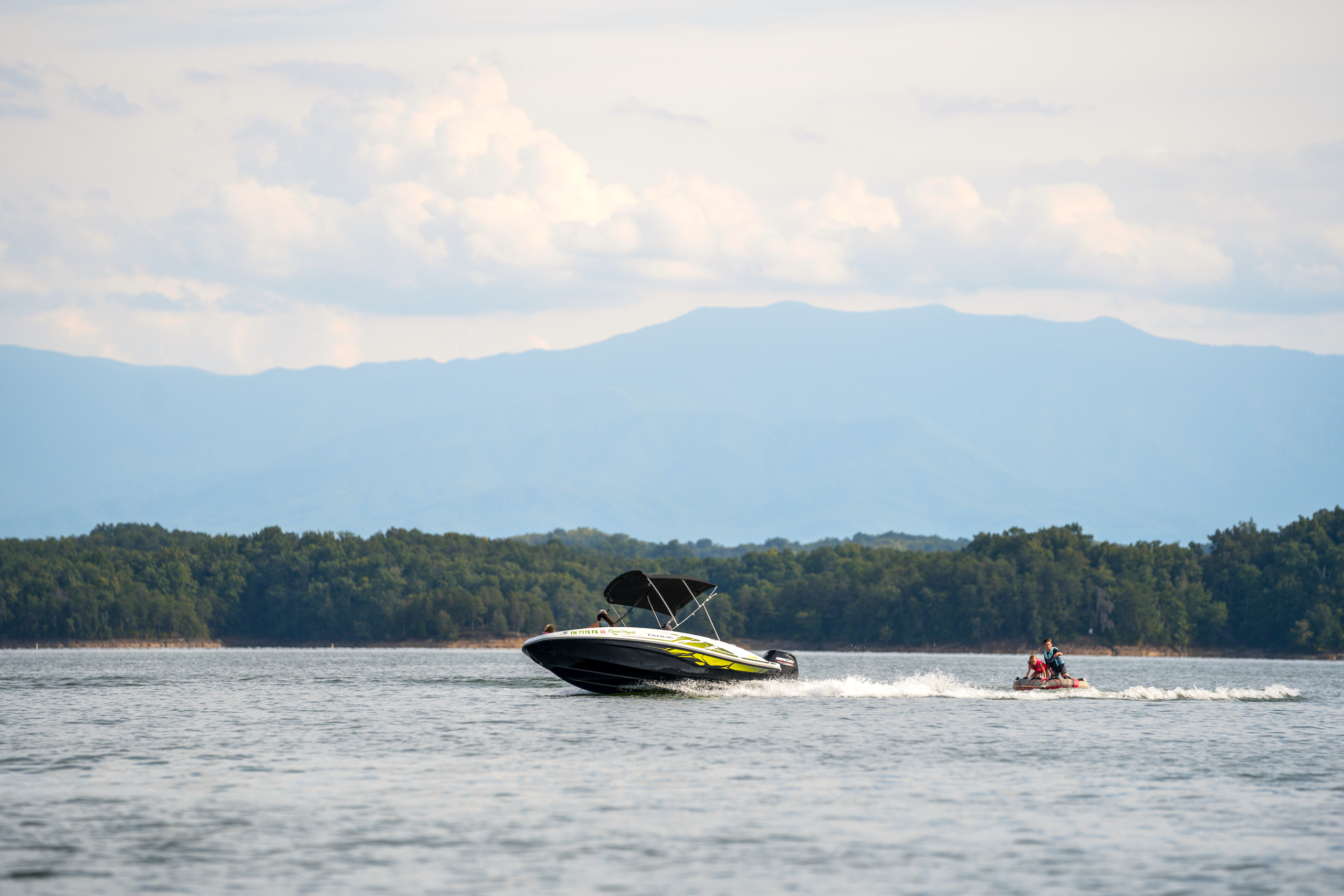 Boat pulling kids on an inter tube on Douglas Lake with Smoky Mountains in the background