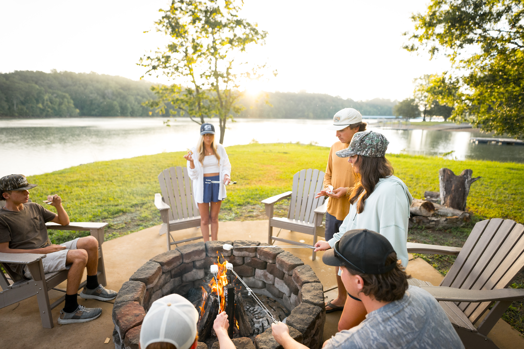 A group of friends toasting marshmallows next to Douglas Lake with sunsetting in the background